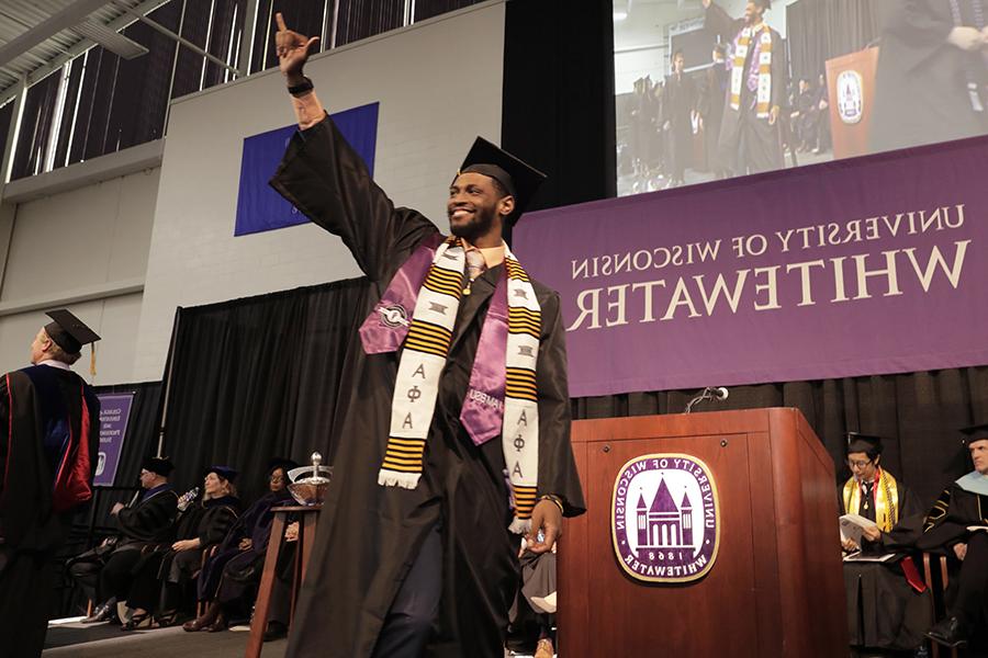 A student celebrates as they cross the stage during graduation.