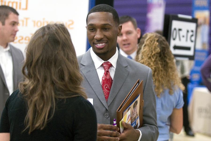 A young student wearing a suit and tie mingles at a career fair.