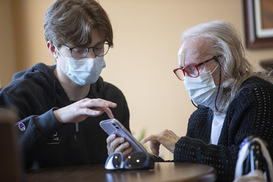 A student and a senior citizen look at a phone together.