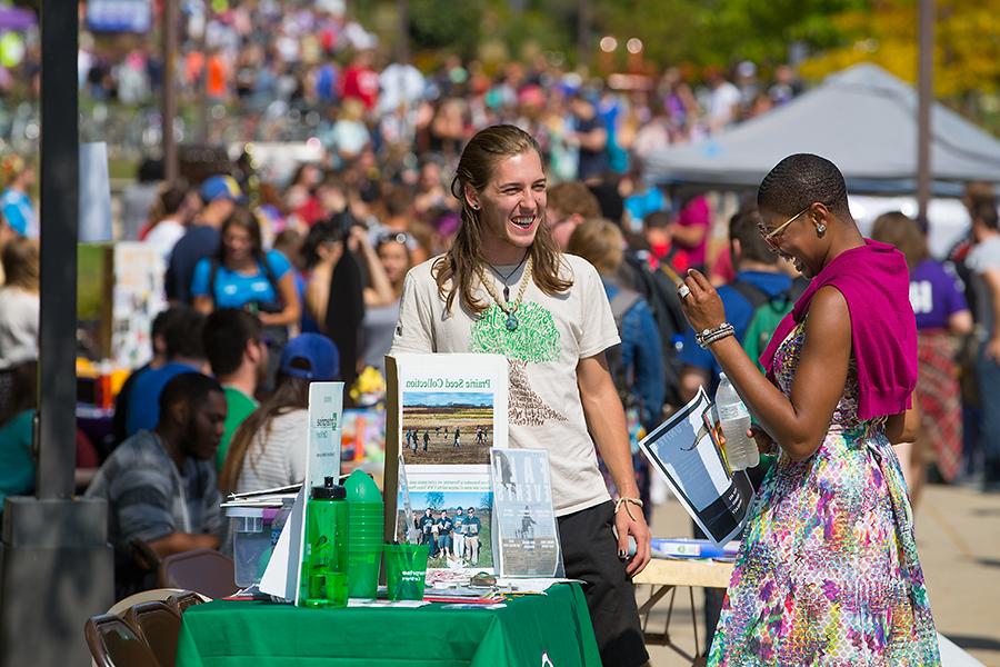 A member of the chancellor's cabinet shares a laugh with a student.