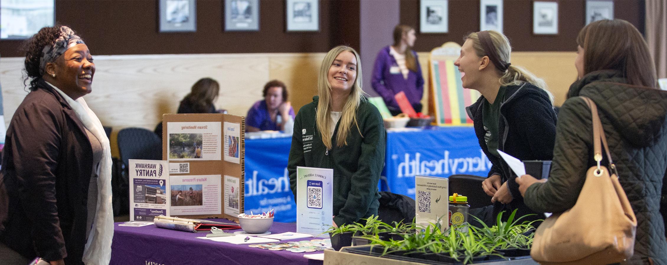 People smile and laugh together as they gather around a table during a benefits fair.